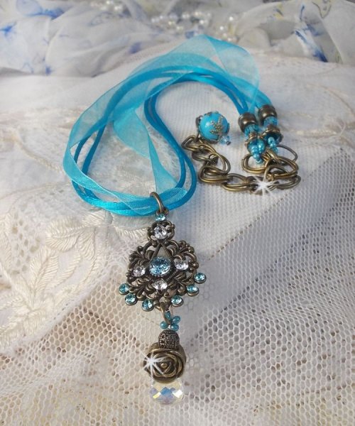 Pendentif Lady in Blue mont&eacute; avec des chandeliers, des cristaux : cabochons, perles rondes et toupies, perles en c&eacute;ramique, cabochons Zirconium, rocailles et rubans. Tout est de couleur Bleu et Bronze