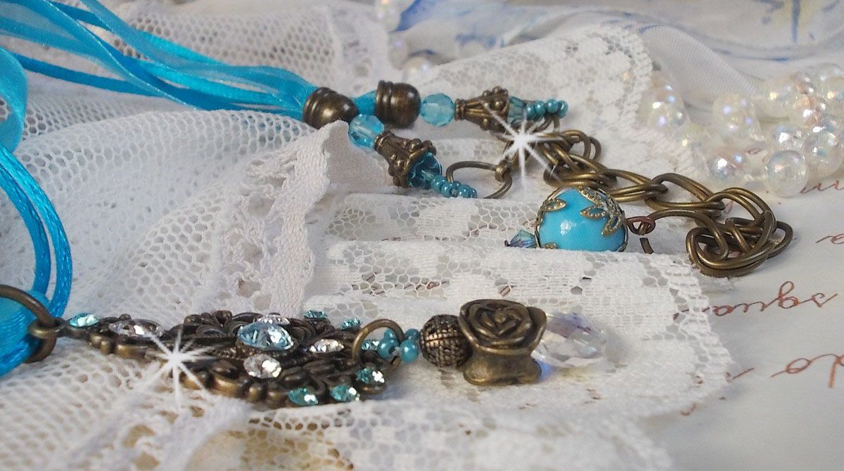 Collier pendentif Lady in Blue monté avec des cristaux de Swarovski, des intercalaires fleurs, des coupelles feuillage et des rubans