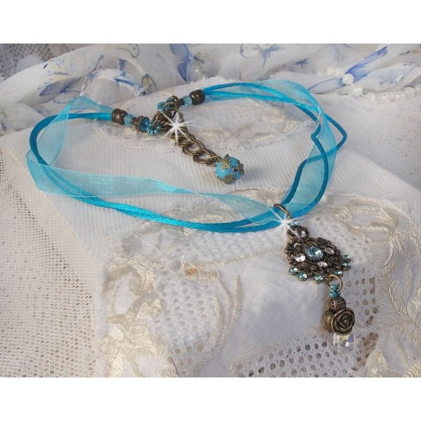 Pendentif Lady in Blue mont&eacute; avec des chandeliers, des cristaux : cabochons, perles rondes et toupies, perles en c&eacute;ramique, cabochons Zirconium, rocailles et rubans. Tout est de couleur Bleu et Bronze