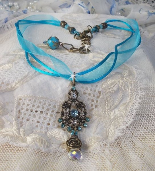 Pendentif Lady in Blue mont&eacute; avec des chandeliers, des cristaux : cabochons, perles rondes et toupies, perles en c&eacute;ramique, cabochons Zirconium, rocailles et rubans. Tout est de couleur Bleu et Bronze