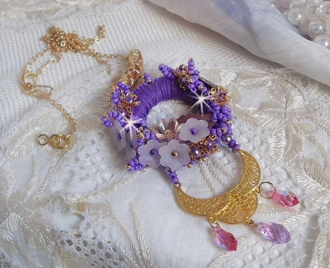 Pendentif Laureline brodé avec un fil coton Violet, monté avec des cristaux, fleurs lucites, perles nacrées, calottes dorées, rocaille, pendentif sur une chaîne en plaqué Or. Un voile de douceur