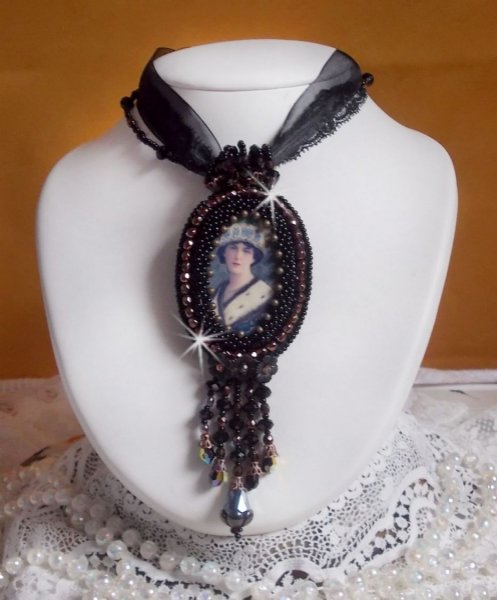 Pendentif Midnight Daisy avec un cabochon en bois repr&eacute;sentant une femme en chapeau Bleu, brod&eacute; avec des fleurs lucites, coupelles et facettes. Le tout est fini avec une dentelle Noire et un ruban