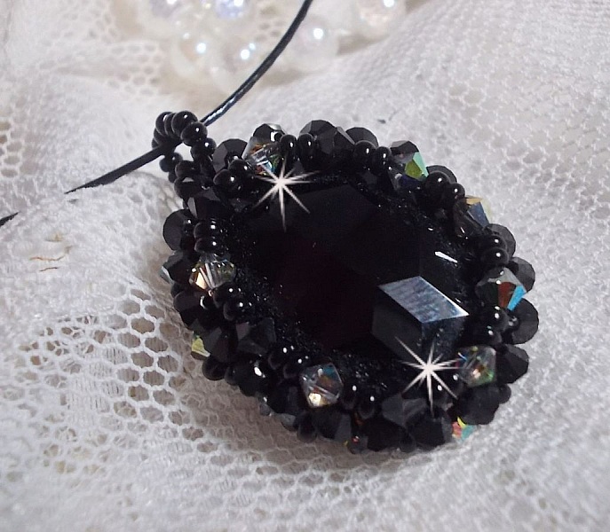 Pendentif Mirano incarne parfaitement l&rsquo;&eacute;l&eacute;gance avec un cabochon ovale facett&eacute; en Cristal cercl&eacute; de rocailles et toupies aux couleurs Noires et Argent&eacute;es. Mont&eacute; sur un tour du cou c&acirc;bl&eacute; et cir&eacute; Noir 