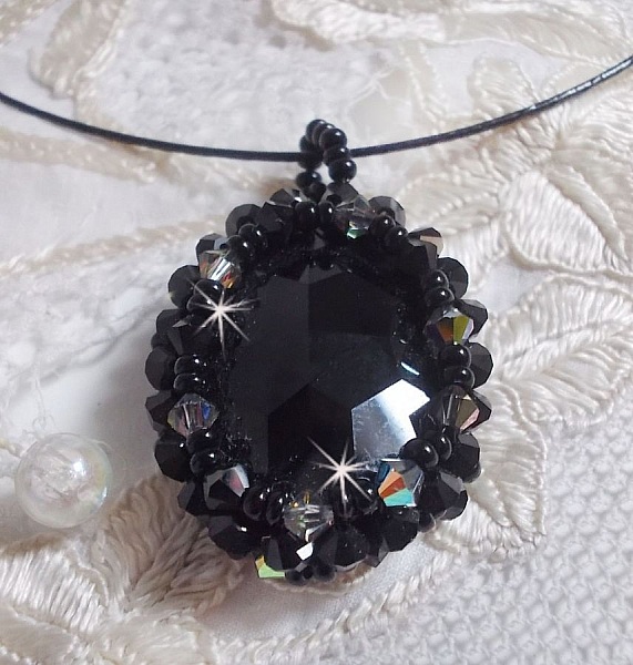 Pendentif Mirano incarne parfaitement l&rsquo;&eacute;l&eacute;gance avec un cabochon ovale facett&eacute; en Cristal cercl&eacute; de rocailles et toupies aux couleurs Noires et Argent&eacute;es. Mont&eacute; sur un tour du cou c&acirc;bl&eacute; et cir&eacute; Noir 