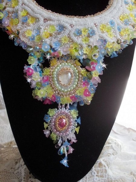 Plastron Envol&eacute;e Fleurie Haute Couture brod&eacute; avec des cabochons Nacre et R&eacute;sine aux couleurs Fuchsia et Ivoire, s&rsquo;ajoute des fleurs lucites, feuilles en verre, chatons et perles en Cristal.