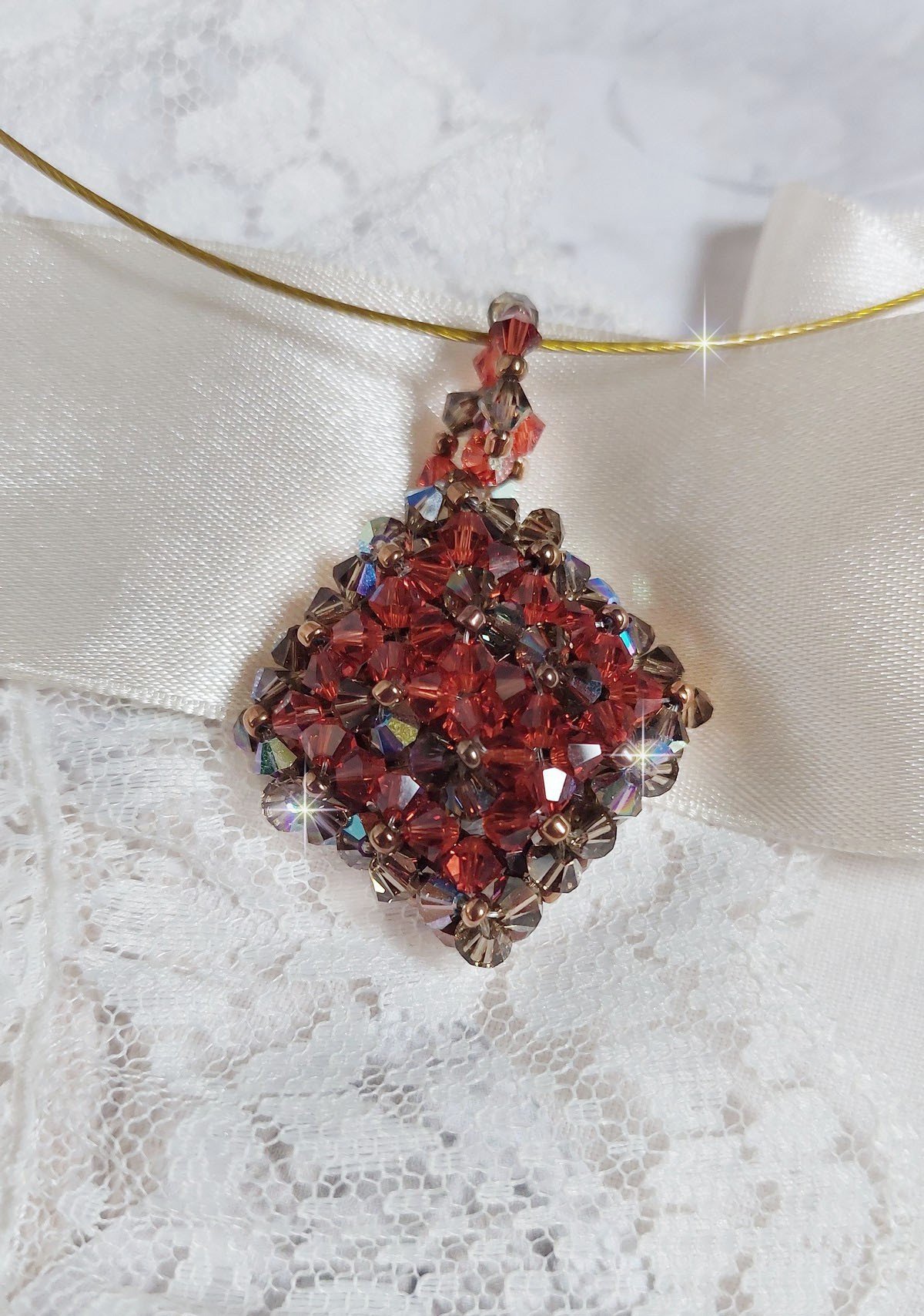 Pendentif Camel mont&eacute; avec des toupies en cristal Indian Red et Smoked Topaz de qualit&eacute; AB sur une base de facettes Dark Bronze et sur un tour de cou c&acirc;bl&eacute; rigide Dor&eacute; avec un fermoir &agrave; vis Argent&eacute;
