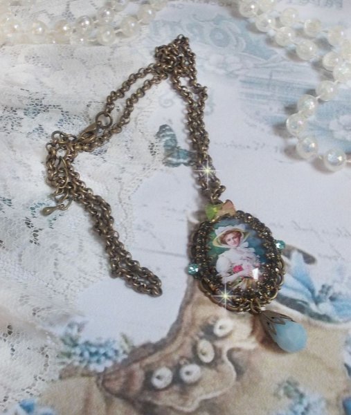 Pendentif Douce Dame créé avec un cabochon représentant une femme au chapeau blanc orné de cristaux, des accessoires de couleur Bronze et un jade teinté bleu 