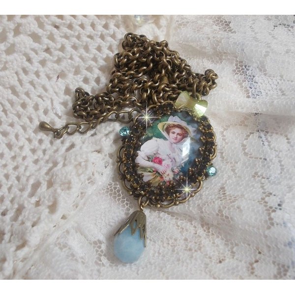 Pendentif Douce Dame créé avec un cabochon représentant une femme au chapeau blanc orné de cristaux, des accessoires de couleur Bronze et un jade teinté bleu 