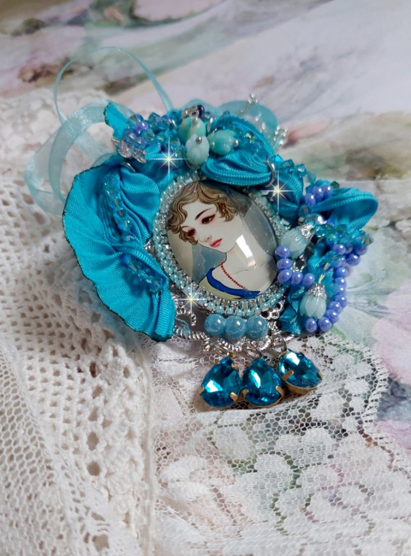 Pendentif Mademoiselle au style rétro avec cabochon d’une femme souriante, orné d’un ruban de soie Bleu, cristaux, perles verre : rocailles et roses, coupelles et chaîne Argent 925/1000
