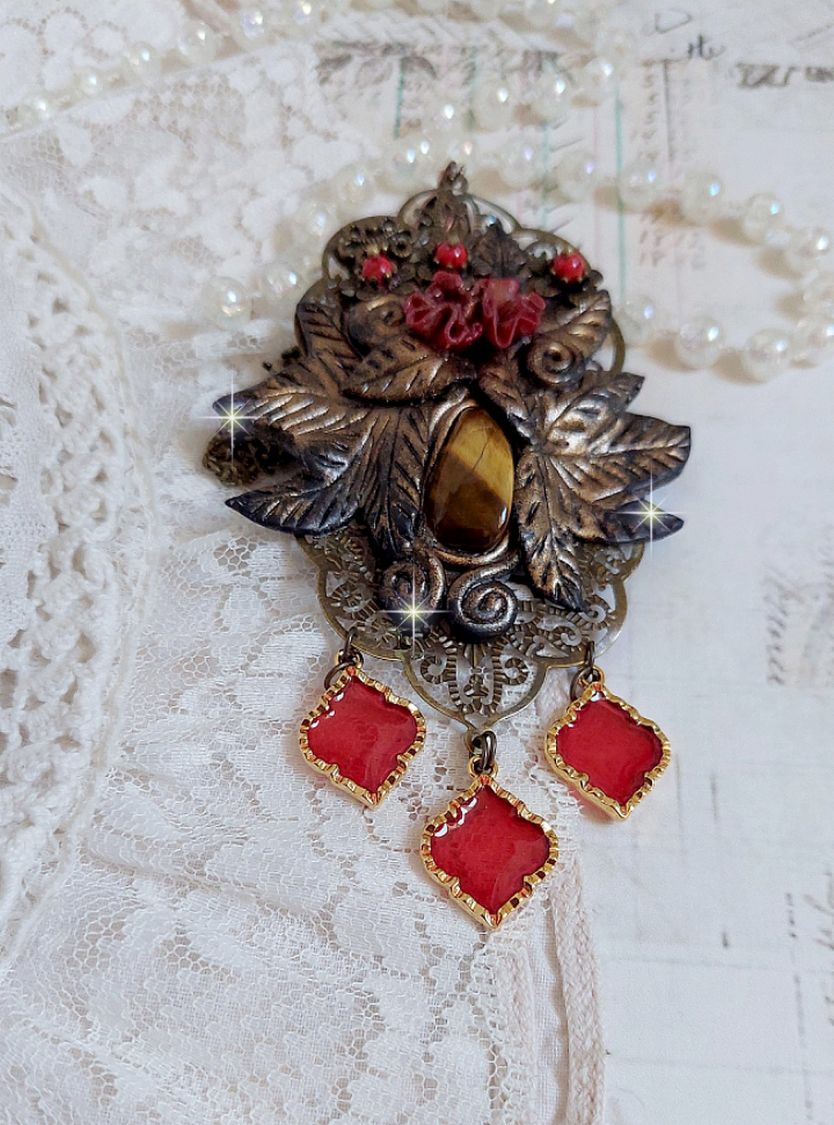 Pendentif Mélodie avec un cabochon Œil de tigre orné de perles en Jade Rouge veiné de Noir sur fleurs 5 pétales et estampes montés sur une chaîne bronze. Les pendants sont en résine époxy Rouge