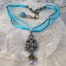 Pendentif Lady in Blue monté avec des chandeliers, des cristaux : cabochons, perles rondes et toupies, perles en céramique, cabochons Zirconium, rocailles et rubans. Tout est de couleur Bleu et Bronze