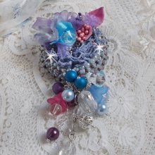 Broche Mademoiselle Bluse Haute Couture brodé avec dentelle Gris perlé, rubans : satin et organza, fleurs en tissu à laquelle s’ajoute des cristaux : perles, navette, toupies et fleurs en résine